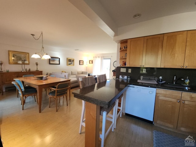 kitchen featuring backsplash, a breakfast bar, white dishwasher, sink, and hardwood / wood-style flooring