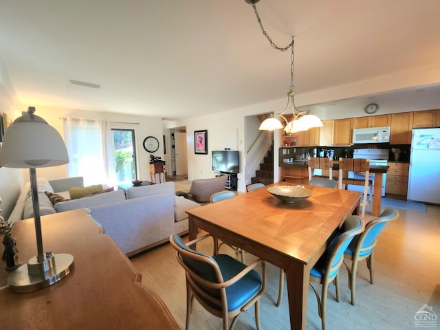 dining area with light wood-type flooring and a chandelier