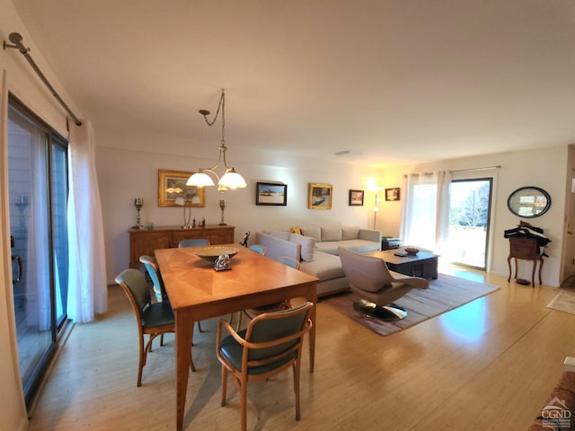 dining area with light hardwood / wood-style floors and a notable chandelier