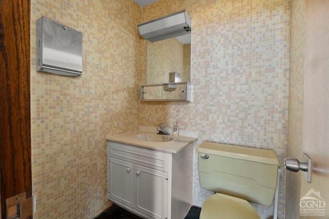 bathroom featuring vanity, toilet, and tile walls