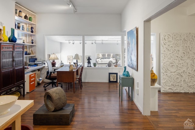 office space featuring built in desk, dark wood-type flooring, and track lighting