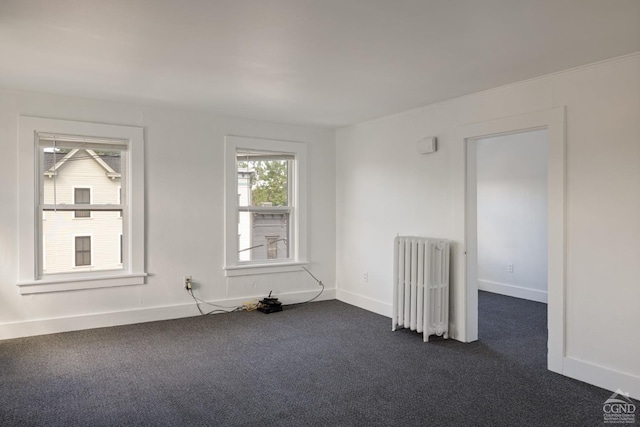 spare room featuring radiator heating unit and dark carpet