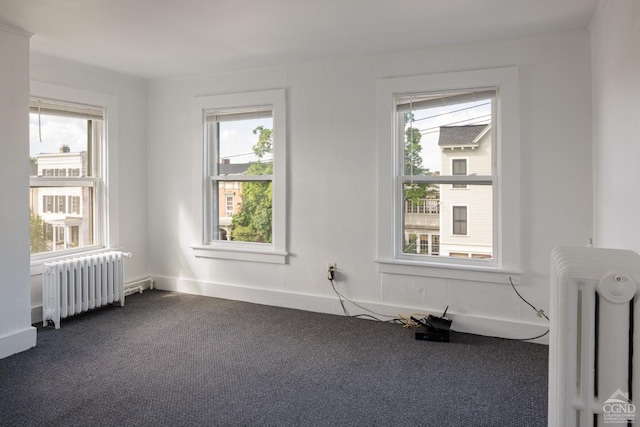 carpeted spare room featuring radiator and a healthy amount of sunlight