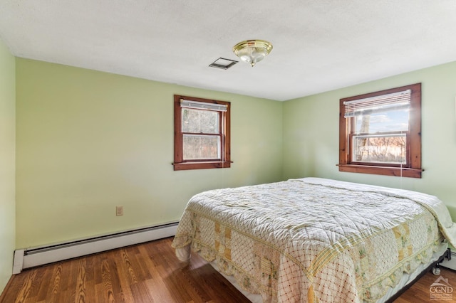 bedroom featuring dark hardwood / wood-style flooring, multiple windows, and a baseboard radiator