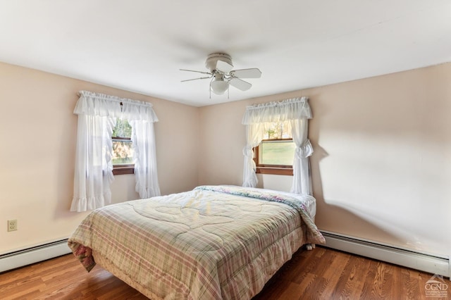 bedroom featuring hardwood / wood-style floors, ceiling fan, a baseboard heating unit, and multiple windows