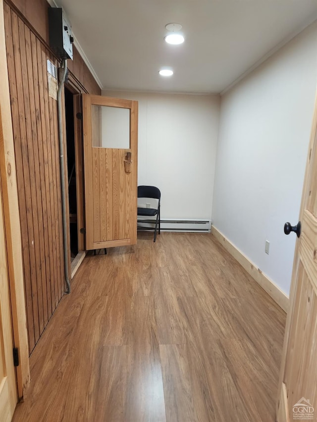 empty room featuring light hardwood / wood-style floors, ornamental molding, and a baseboard radiator