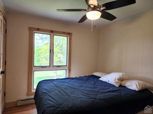 bedroom featuring light wood-type flooring, baseboard heating, crown molding, and ceiling fan