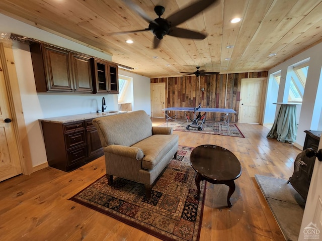 living area featuring wooden walls, sink, wood ceiling, and light wood-type flooring