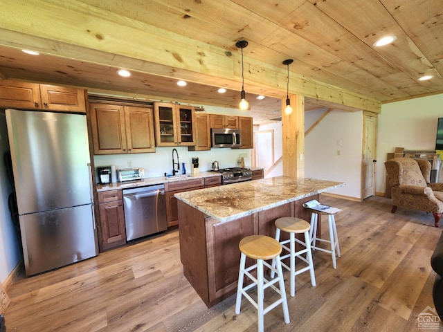 kitchen with decorative light fixtures, light stone countertops, stainless steel appliances, and light hardwood / wood-style flooring