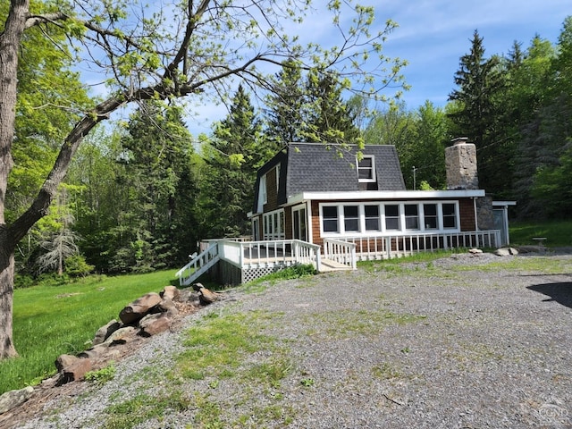 exterior space with a wooden deck, a sunroom, and a yard