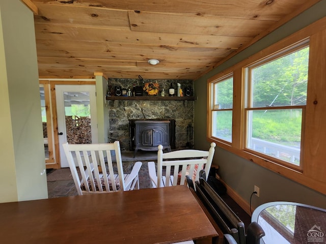 dining area featuring a wood stove and wooden ceiling