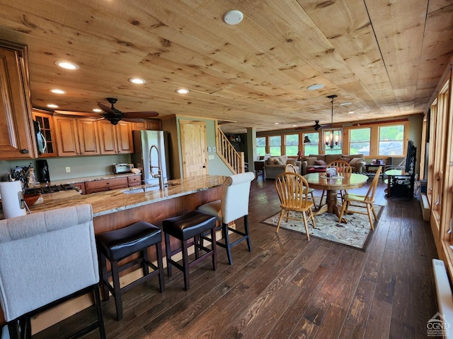 kitchen with sink, ceiling fan, dark hardwood / wood-style flooring, light stone counters, and wood ceiling