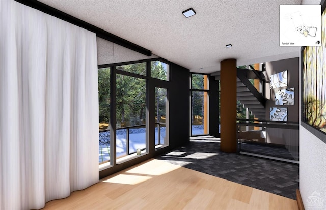 entryway featuring hardwood / wood-style floors, a healthy amount of sunlight, a textured ceiling, and a wall of windows