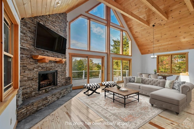 living room featuring beam ceiling, a healthy amount of sunlight, a stone fireplace, high vaulted ceiling, and light hardwood / wood-style floors