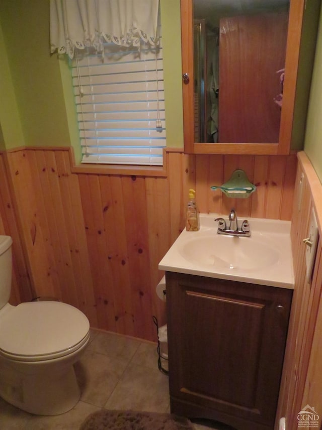 bathroom featuring tile patterned flooring, vanity, toilet, and wood walls