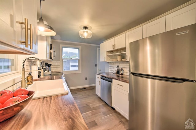 kitchen featuring sink, tasteful backsplash, appliances with stainless steel finishes, white cabinets, and hardwood / wood-style flooring