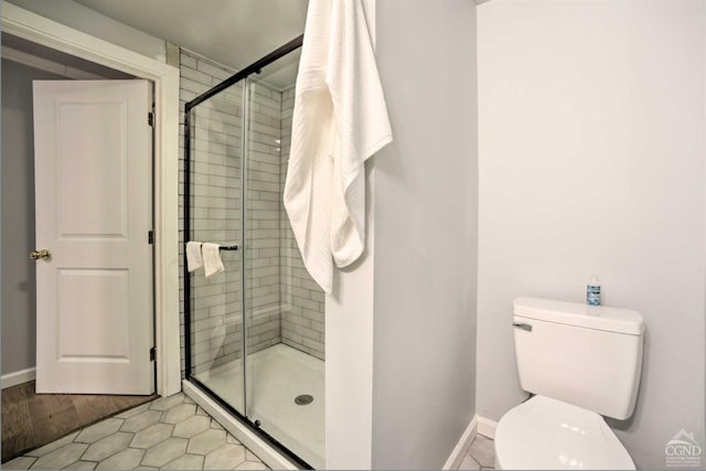 bathroom with tile patterned floors, toilet, and a shower with door