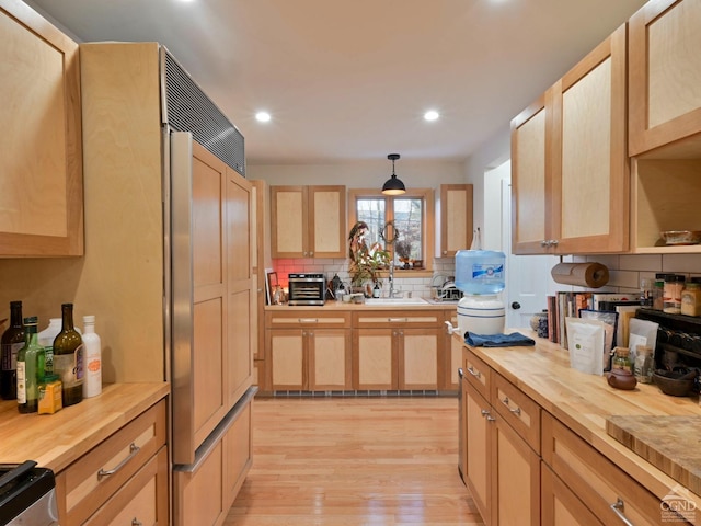 kitchen with light brown cabinetry, hanging light fixtures, light wood-type flooring, and wood counters