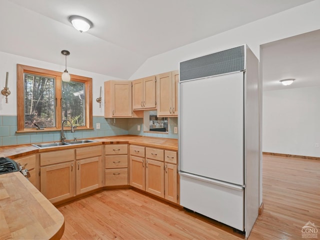 kitchen featuring pendant lighting, light brown cabinets, sink, decorative backsplash, and paneled refrigerator