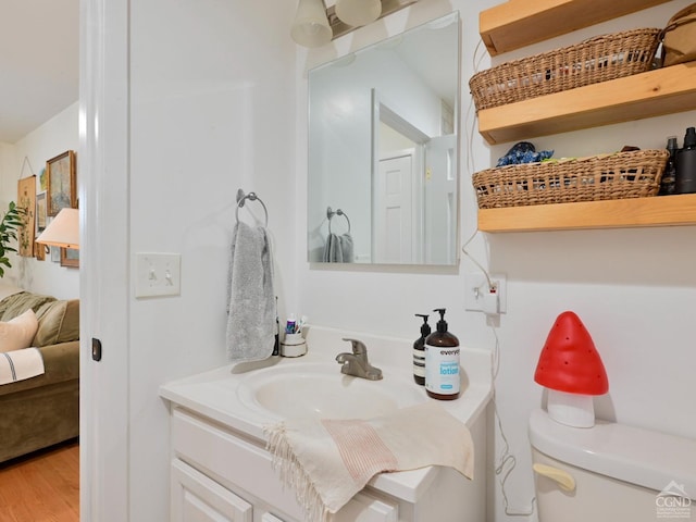 bathroom with wood-type flooring, vanity, and toilet