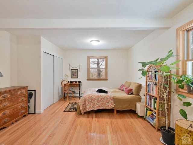 bedroom with light hardwood / wood-style floors, baseboard heating, and multiple windows