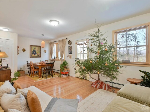 living room with hardwood / wood-style flooring, baseboard heating, and a healthy amount of sunlight