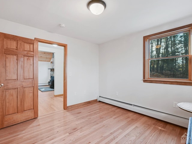 unfurnished room featuring light hardwood / wood-style flooring and a baseboard heating unit