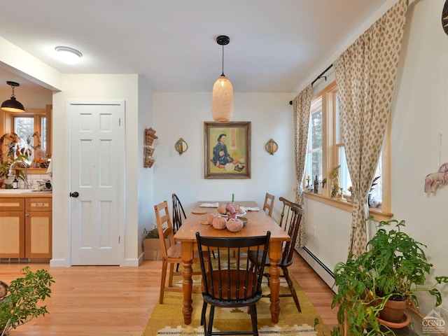 dining area featuring light wood-type flooring, sink, and a baseboard heating unit