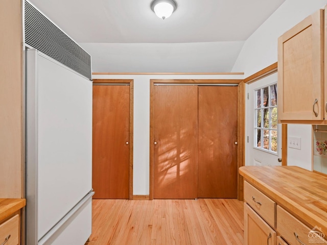 kitchen featuring light brown cabinets, paneled built in refrigerator, light hardwood / wood-style floors, and vaulted ceiling