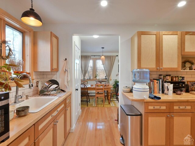 kitchen featuring tasteful backsplash, sink, pendant lighting, light brown cabinets, and light hardwood / wood-style floors