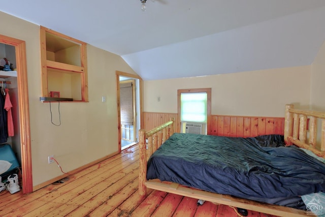 bedroom with wood walls, light hardwood / wood-style flooring, and lofted ceiling