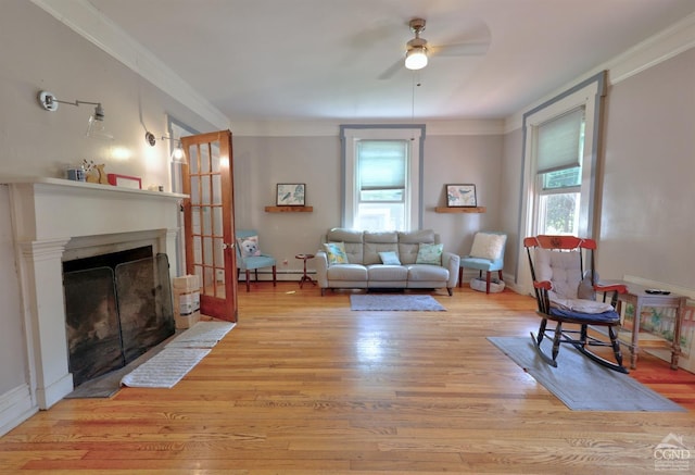 living room featuring plenty of natural light, ornamental molding, and light wood-type flooring