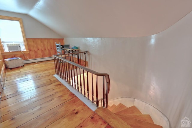 staircase with cooling unit, hardwood / wood-style flooring, a baseboard radiator, lofted ceiling, and wood walls