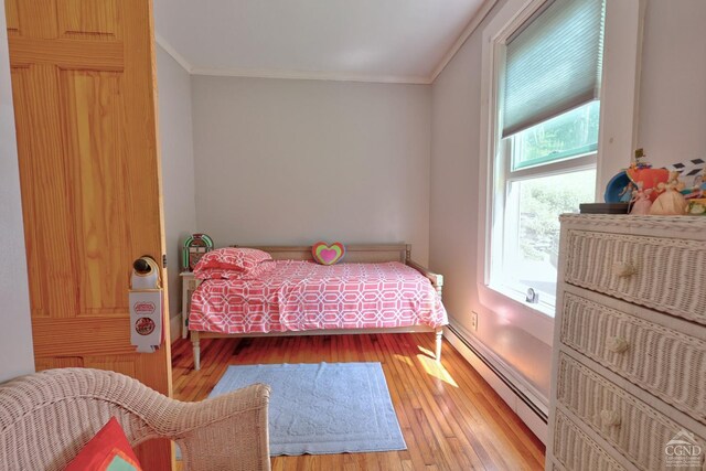 bedroom with a baseboard radiator, light hardwood / wood-style flooring, and ornamental molding