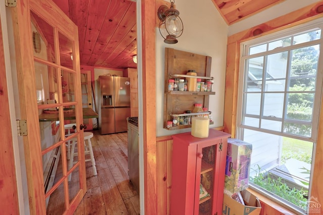 interior space featuring plenty of natural light, stainless steel fridge with ice dispenser, and wooden ceiling