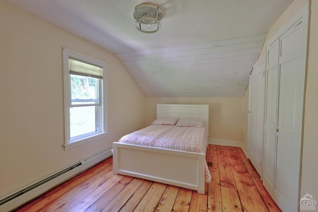 bedroom with a baseboard heating unit, light wood-type flooring, and lofted ceiling