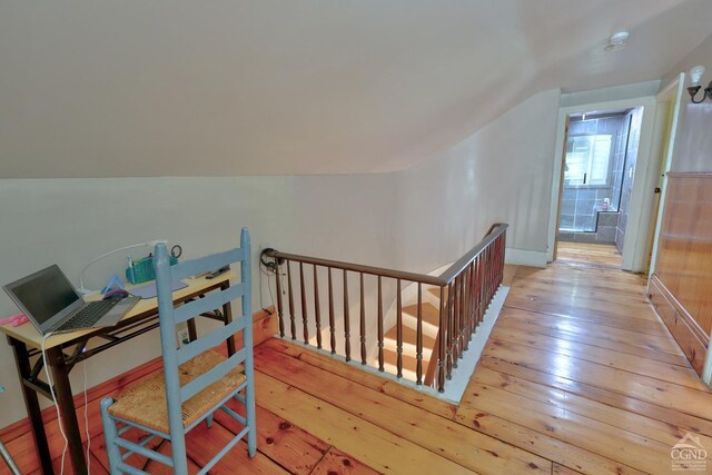 hallway with light wood-type flooring and vaulted ceiling