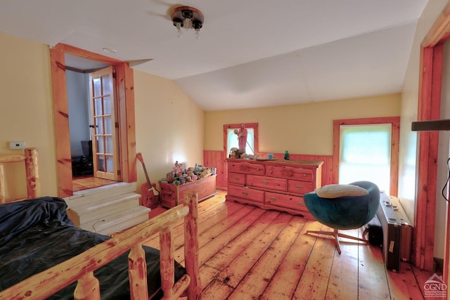 bedroom featuring radiator heating unit, light hardwood / wood-style flooring, and vaulted ceiling