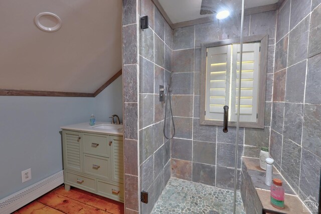 bathroom with baseboard heating, lofted ceiling, a shower with door, vanity, and tile walls