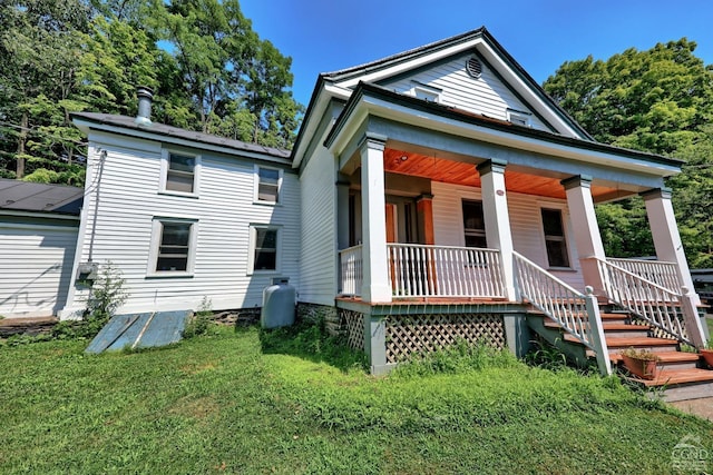 rear view of house with covered porch and a yard