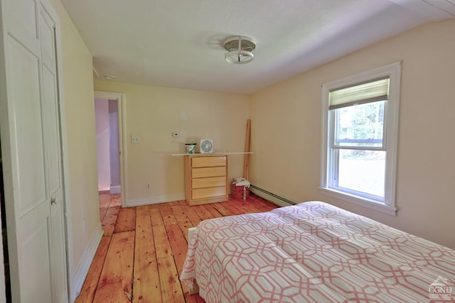 unfurnished bedroom featuring light hardwood / wood-style floors, a closet, and a baseboard heating unit