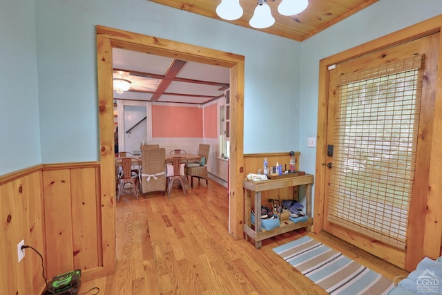 doorway to outside with beam ceiling, coffered ceiling, crown molding, a chandelier, and light hardwood / wood-style floors