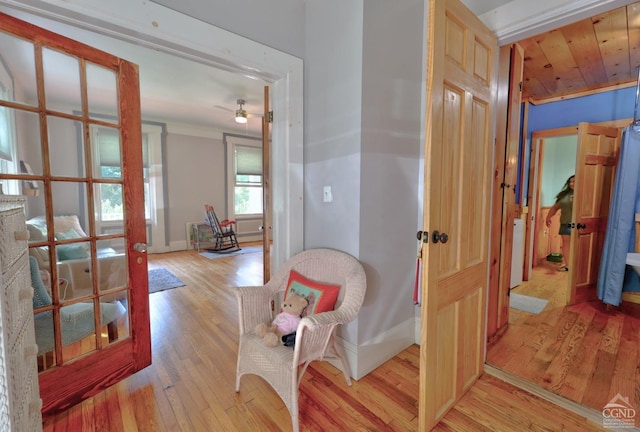 hall with light hardwood / wood-style floors, ornamental molding, and wood ceiling