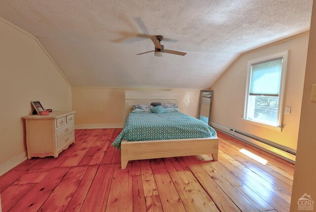 bedroom with ceiling fan, a baseboard heating unit, hardwood / wood-style floors, a textured ceiling, and vaulted ceiling