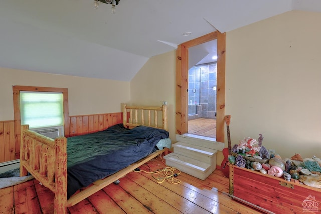 bedroom with cooling unit, a baseboard radiator, hardwood / wood-style floors, connected bathroom, and lofted ceiling