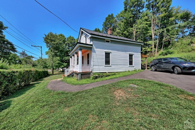 view of side of home with a lawn and covered porch