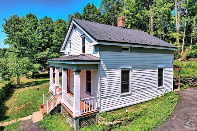 view of side of home featuring a porch and a yard