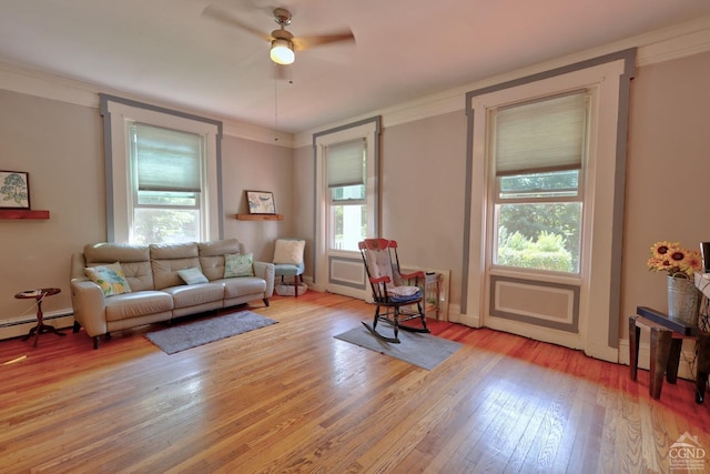 living room featuring light wood-type flooring, plenty of natural light, ornamental molding, and ceiling fan