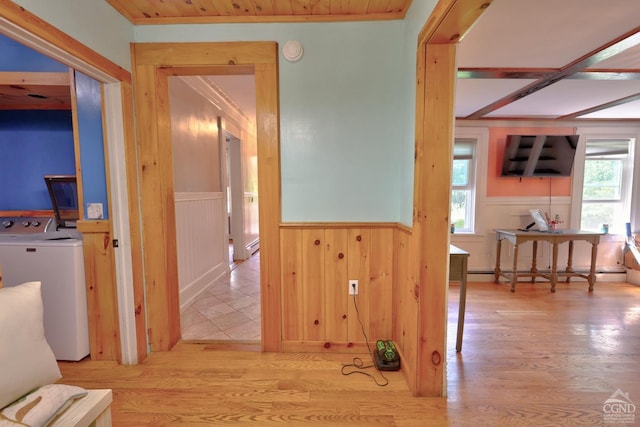 hall with light wood-type flooring, washer / clothes dryer, baseboard heating, and plenty of natural light