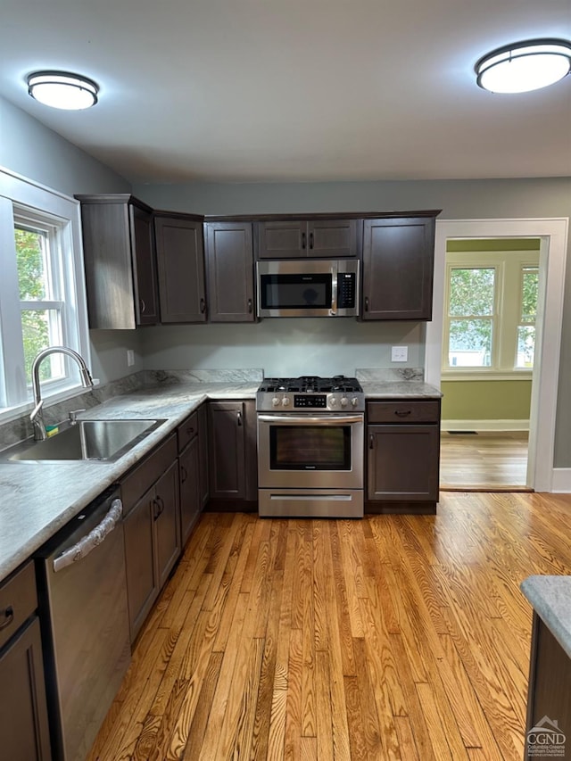 kitchen with sink, light wood-type flooring, stainless steel appliances, and dark brown cabinetry